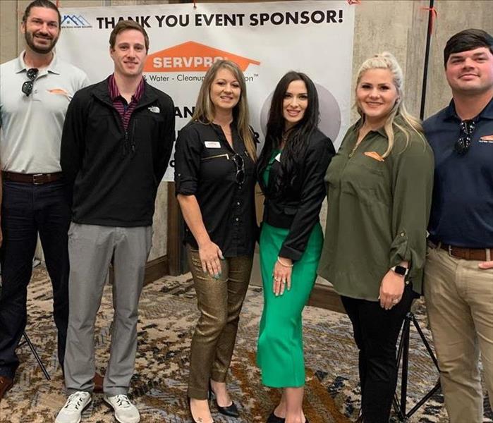 SERVPRO employees in front of white sign