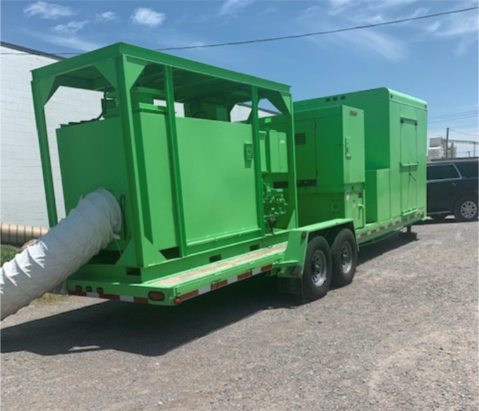 Large green drying equipment in parking lot outside warehouse