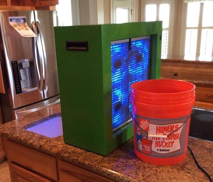 green box and orange 5 gallon bucket on kitchen counter