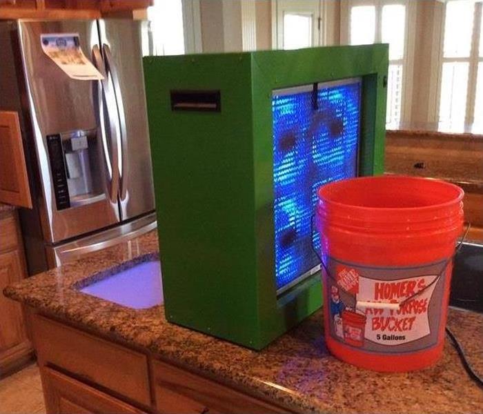 green equipment, orange bucket on kitchen counter