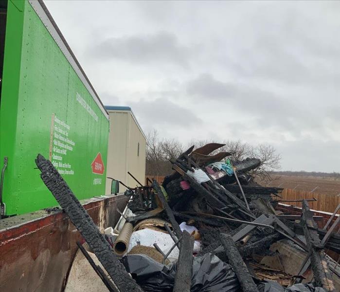 green SERVPRO truck, dumpster with damaged household goods