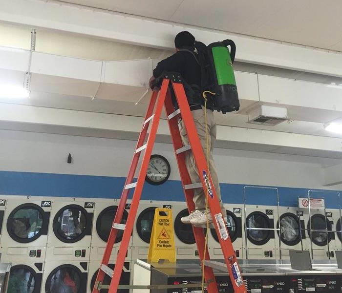 man on orange ladder at laundromat